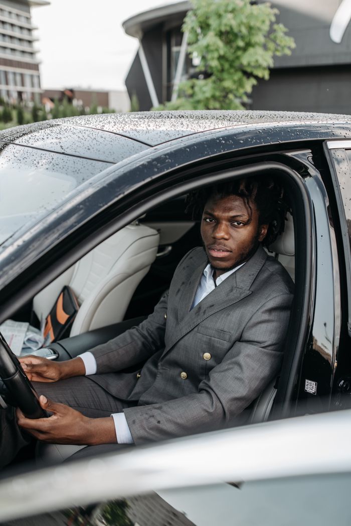 Stylish man in a gray suit seated in a luxury car, ready for a drive.